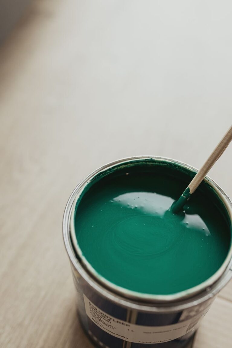 A detailed close-up of a fresh can of green paint being stirred with a stick, perfect for DIY projects.